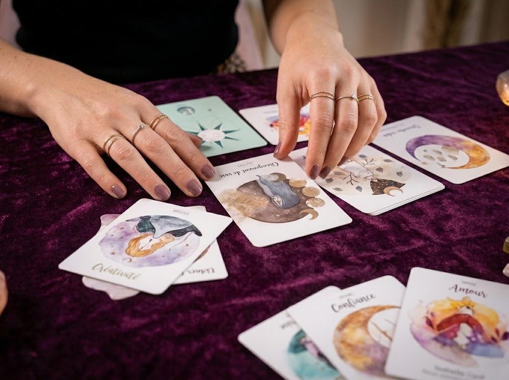 Mains disposant des cartes d'oracle sur un tapis de velours violet